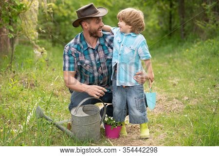 Father And Son In Nature With Watering Can. Gardening Tools. Planting Tree. Dad Teaching Little Son 