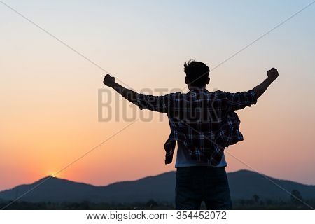 Man With Fist In The Air During Sunset Sunrise Mountain In Background. Stand Strong. Feeling Motivat