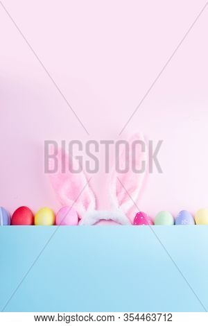 Easter Rabbit Flaffy Ears And Colored Easter Colored Eggs, Top View Flat Lay On Pink And Blue Plain 