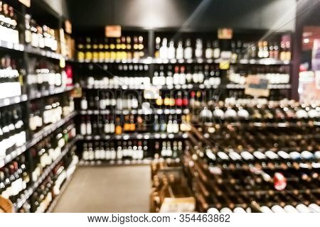 Blurred Wine Section Of Retailer With Bottles On Shelf Display Rack
