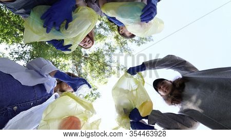 Group Of Activists Friends Throw A Lot Of Garbage In A Bag. Bottom-up Shooting