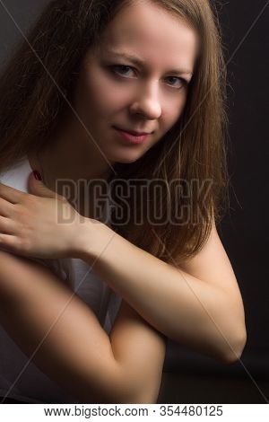 Brown-haired Girl On A Black Background In White Blouse. Contemptuous Look. Hands At The Collar