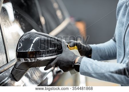 Man Applying Sticking Protective Film On A Car Mirror At The Vehicle Service Station, Cllose-up. Con