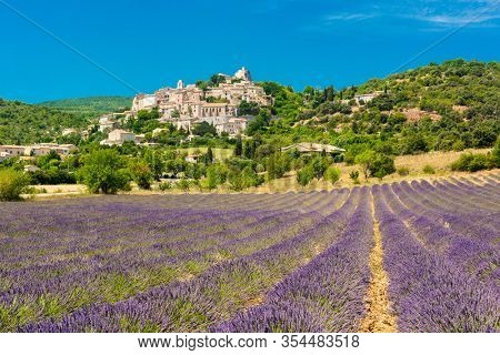 Small but beautiful old town of Simiane la Rotonde with a lavender field in front of it, Provence - France