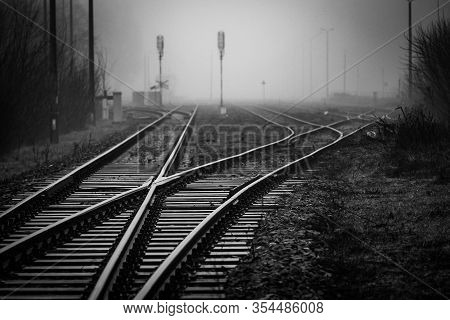 Railroad Junction With Track Switches Disappearing In Mist - Monochrome Image