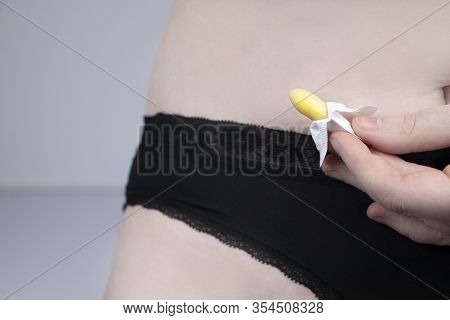 Vaginal Or Rectal Candle In The Hands Of A Woman Against The Background Of The Abdomen And Underwear