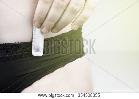 Vaginal Or Rectal Candle In The Hands Of A Woman Against The Background Of The Abdomen And Underwear