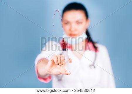 Young Girl Doctor Holding Syringe With Blood In His Hand In A White Coat And Mask On Her Face