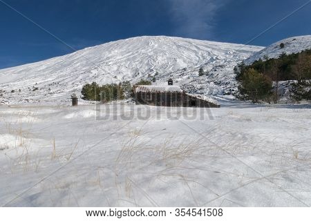 snow covered Etna Mount and below stone Palestra or Poggio La Caccia refuge, one of the highest refuge in Etna Park, Sicily 