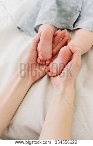 Mother Holding Feet Of Her Little Baby Daughter