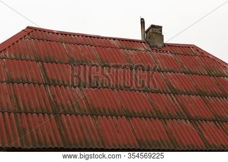 Old Red Eternit Fibre Cement Covered With Moss. Chimney On The Roof.
