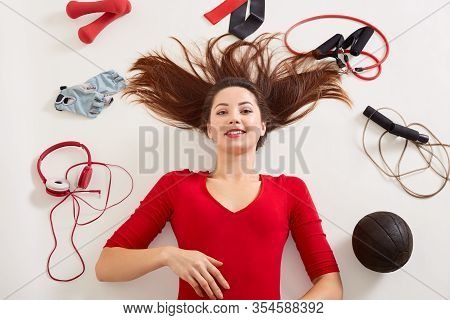Woman Lying On Floor After Working Out With Dumbbell, Skipping Rope, Fitness Gloves, Expander, Elast