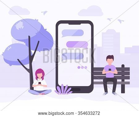 Young Woman And Young Man Sitting In City Park Near Big Smartphone With The Message Bubbles On Scree