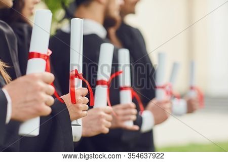 Scrolls Of Diplomas In The Hands Of A Group Of Graduates.