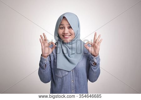 Portrait Of Beautiful Asian Muslim Woman Smiling While Making Delicious Hand Gesture With Her Finger