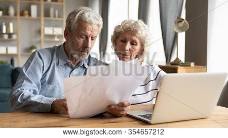 Elderly Husband And Wife Read Documents Pay Bills Online