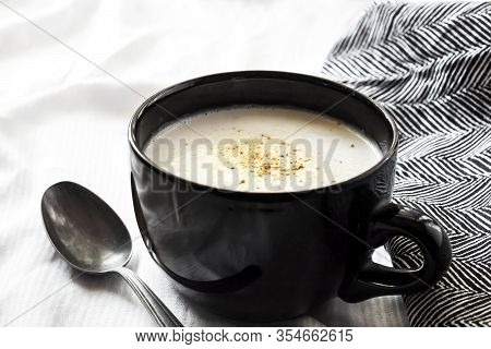 Cauliflower Soup (creme Du Barry) In Black Bowl On White Background With Black And White Cloth.