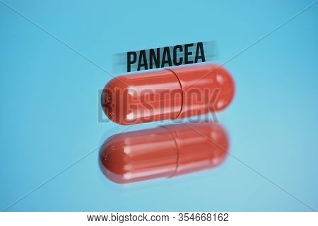 Red Capsule With Abstract Inscription Panacea On A Blue Background. Close Up.