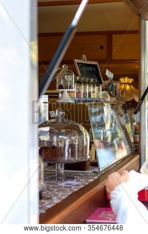 A Portrait Of A Market Stall With Cake And Other Pastries Inside. The Stall Is Filled With Glass Dom