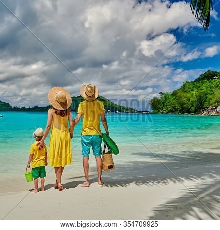 Family on beach, young couple in yellow with three year old boy. Summer vacation at Seychelles. Port Launay, Mahe. 