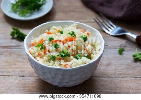 Vegetarian Rice Dish With Vegetables And Green Peas On A Wooden Background.