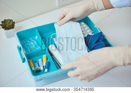 Hand In Gloves Take Protective Midicine Mask From First Aid Kit. Home Medicine Box With A Medical It