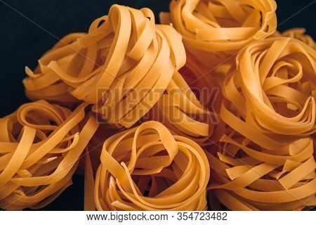 Pasta Alluovo, Tagliatelle Pasta, Round Balls Of Raw Pasta On Black Background, Close Up Of A Raw Dr
