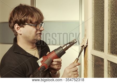 Man At Home Removing Havy Layer Of Old Paint From Door