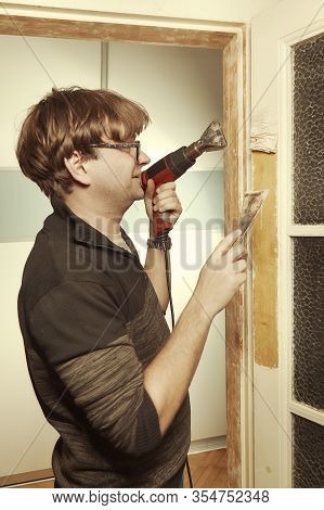 Man At Home Removing Havy Layer Of Old Paint From Door