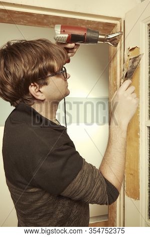 Man At Home Removing Havy Layer Of Old Paint From Door