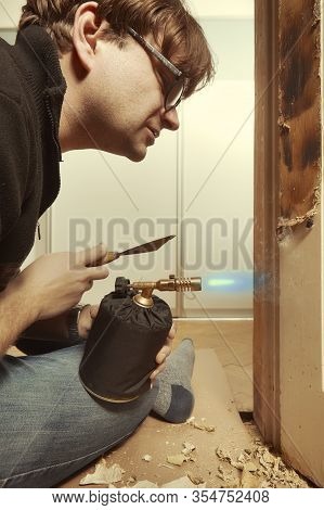 Man At Home Removing Havy Layer Of Old Paint From Door With Burner