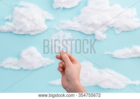 Child Holding A Cut Out Showflake On Blue Sky Background