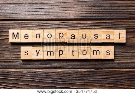 Menopausal Symptoms Word Written On Wood Block. Menopausal Symptoms Text On Wooden Table For Your De