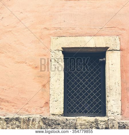 Aged Pink Wall With Window With Bars. Closed Window In A Dismissed Warehouse, Frosted Pane And A Gra