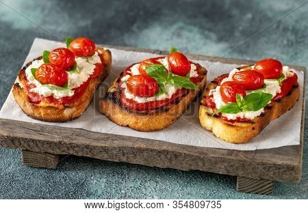 Italian Bruschettas With Mozzarella, Riccotta, Baked Tomatoes And Basil
