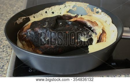 Cooking fail. Burned omelet in pan close-up. Amateur culinary
