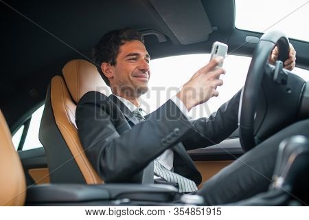Young businessman using his mobile phone while driving, dangerous behaviour concept