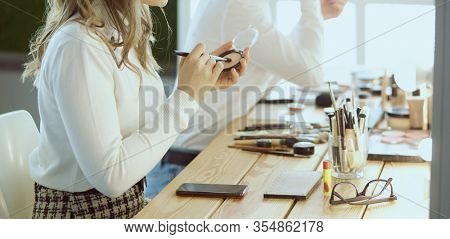 make up artist doing professional make up of young woman