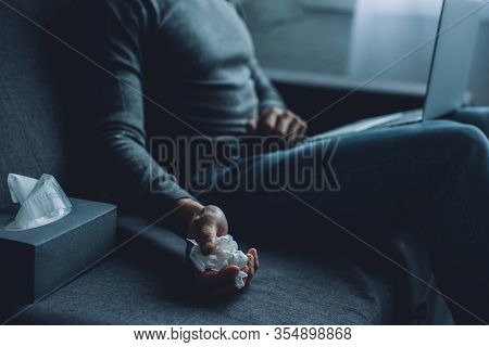Selective Focus Of Man Holding Crumpled Napkin While Watching Pornography On Laptop On Sofa
