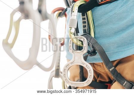 Close-up Of Sportswoman Climber In Safety Harness With Mountaineering Equipment Holding Quickdraws.