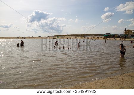 Arabat Spit, Ukraine - August 23, 2017: Unknown People Bathe In The Salt Lake. Composition Of The Wa