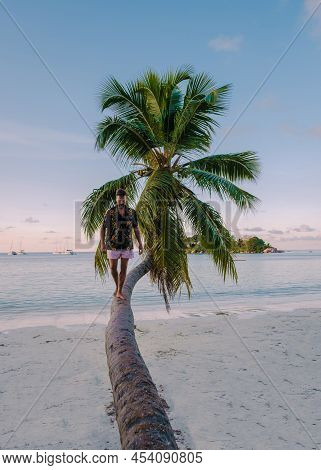 Praslin Seychelles Tropical Island With Withe Beaches And Palm Trees, Men With A Palm Tree At Anse V