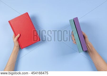 Hands Holding Books Over Light Blue Background. Education, Self-learning, Book Swap, Sharing, Bookcr