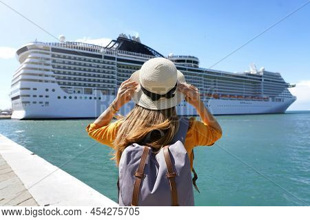 Tourist Girl With Backpack And Hat Standing In Front Of Big Cruise Liner