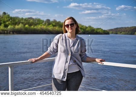 Portrait Of Attractive Caucasian Woman In Sunglasses Posing On A Dock By The River At Warm Summer Su