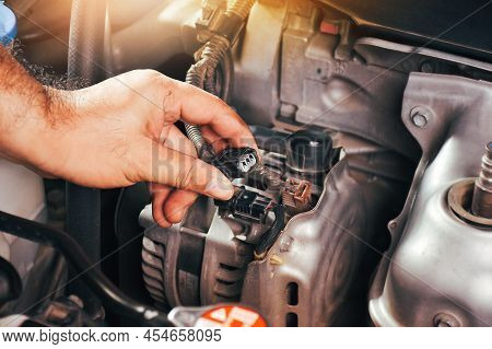 The Auto Mechanic Hand Is Grasping The Car Alternator Charger Plug