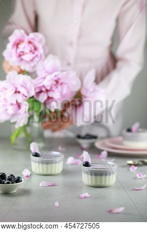Homemade Italian Dessert Panna Cotta With Blue Berries And Bouquet Of Peony Flowers On Gray Backgrou