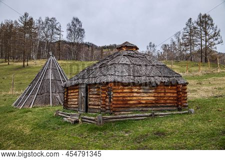 National House Made Of Round Pine Logs In A Forest Clearing In Early Spring. Traditional Dwelling Of