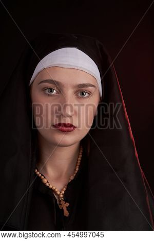 Portrait Of A Young Caucasian Christian Nun Sister Girl. Wearint Wooden Cross. Apathetic Indifferent
