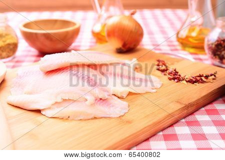 Raw fish tilapia on cutting board and spices